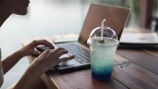 Woman Working On Laptop Outside Enjoying A Refreshing Drink.