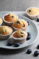 Delicious sweet muffins with blueberries on grey table