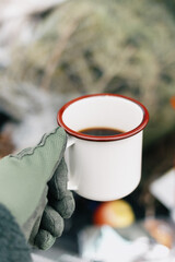 Hand holding specialty coffee in metal mug Off-grid in cold weather while Camping and Hanging out in Nature outdoors