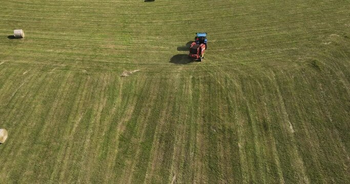 Drone shot depicting a calm farmer's life. Tractor driving through farm fields.