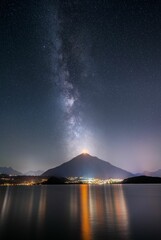 Vertical shot of the Milky Way over Lake Thun and Mount Niesen Lights over the municipality of Spiez