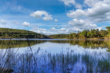 Obraz premium Lake in the woods with beautiful winter blue skies reflections. Bricks water dam in a small village