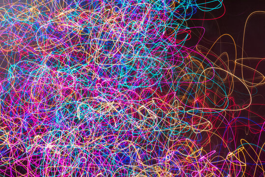 Abstract light painting of multiple bright, glowing neon colors, with a chaotic squiggle pattern that begins to trail off toward the right edge of the image.