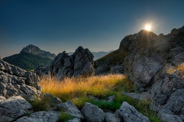 Scenic view of rocky hills covered with green grass at sunrise