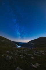 Scenic view of a green mountain range under a starry night sky
