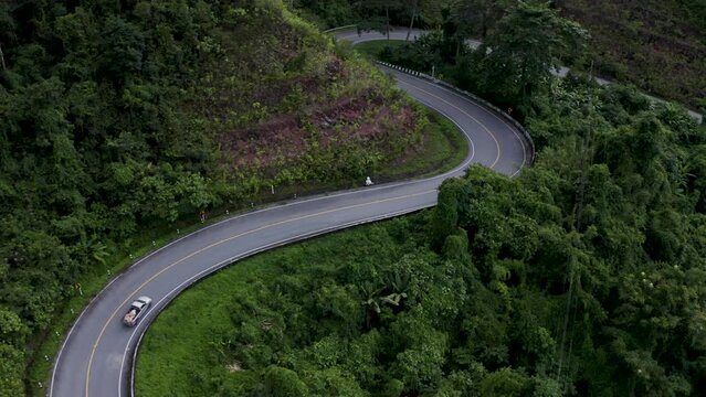 Drone view over curved roads between forested landscapes