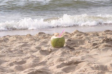 Coconut juice with pink straw on sand beach floor sea view background