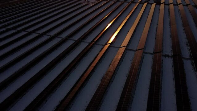 A drone shot of sunrays reflecting on solar panels during sunset.