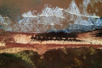 Aerial top view of waves crashing along Cable Head West beach, Prince Edward Island, Canada