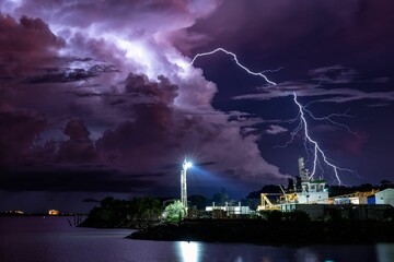 Dramatic shot of bright lightning striking over the shore of a beautiful city