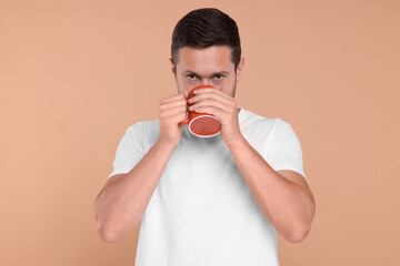 Man drinking from red mug on beige background