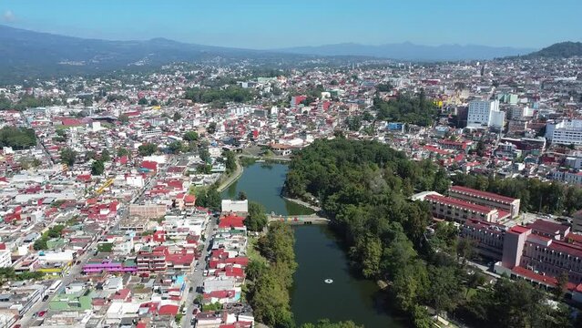 4k forward aerial view drone shot of the walk of the lake bridge surrounded by nature and residential houses of Xalapa, Veracruz at daytime