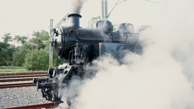 A departing steam historical train disappears into the distance and a thick cloud of white steam. Czech Republic