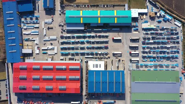 Aerial view of a semi trucks with cargo trailers standing on warehouses ramps for loading unloading goods on the big logistics park with loading hub