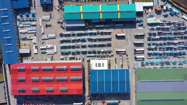Aerial view of a semi trucks with cargo trailers standing on warehouses ramps for loading unloading goods on the big logistics park with loading hub