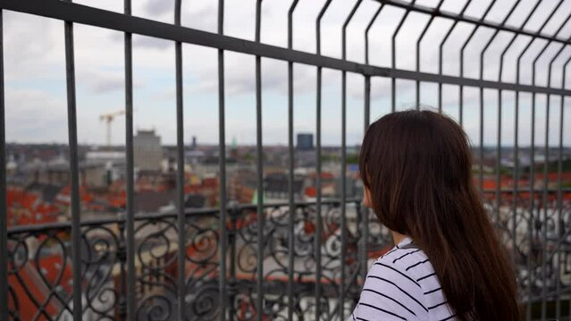 Woman smiles at camera as she enjoys the view of Copenhagen from the top of Rundetaarn. Denmark