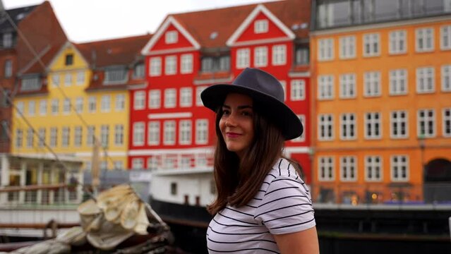 Woman wearing a hat and smiling in Nyhavn with colorful houses in background