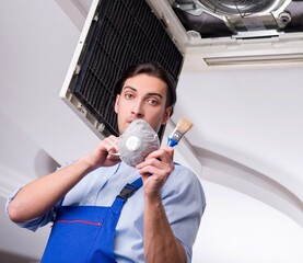 Fototapeta na wymiar Young repairman repairing ceiling air conditioning unit