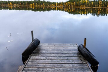 Idyllic scene of a tranquil dock situated on a still body of water surrounded by trees