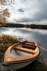 Boat is perched on the water's edge of a tranquil lake surrounded by golden autumn foliage