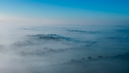 Aerial view of a small town shrouded in a misty fog, with white fluffy clouds surrounding it