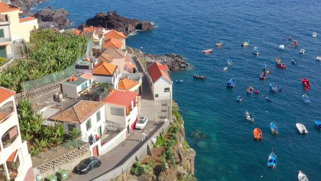 Aerial view of colorful boats on blue water near the shore of Camara de Lobos, Madeira Island
