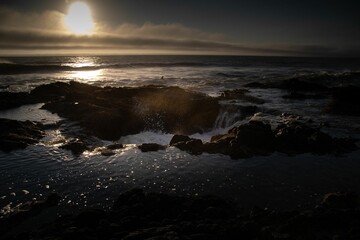 Obraz premium waves crash up against the rocks at sunset on a rocky shore