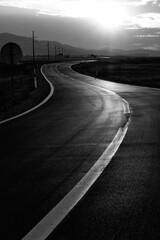 Vertical grayscale of a highway surrounded by rural landscape