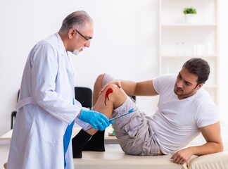 Obraz premium Leg injured man visiting old doctor in first aid concept