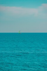 a blue body of water filled with a green sailboat