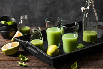 Closeup of green smoothie glasses with fruits and vegetables on a wooden surface