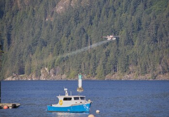 Scenic view of a water bomber flying over a boat in  Vancouver, British Columbia, Canada