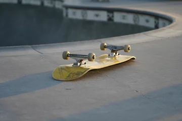 Foto auf Acrylglas Yellow skateboard lying upside down on a skate track © Wirestock
