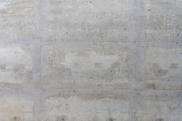 A weathered and cracked concrete wall texture with grey colors, a smooth surface with splotch marks