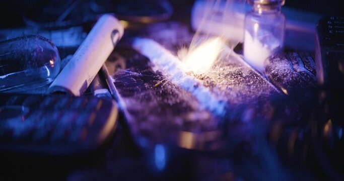 Closeup of a burning powder surrounded by wires and flasks in cold blue tones