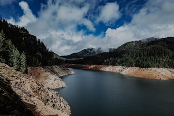 Tranquil lake against a picturesque backdrop of majestic mountains and wispy clouds