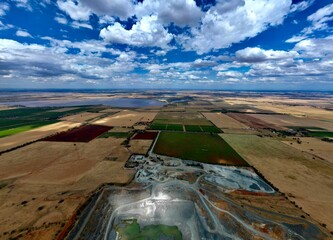 Aerial view of an expansive grassy field with a few cultivated plots of land in the foreground © Wirestock