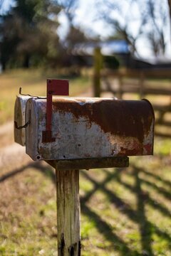 Antiqued metal mail box mounted on a wooden post, featuring a traditional red top
