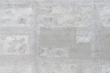 A weathered and cracked concrete wall with smooth surface texture, light to medium grey colors, and...