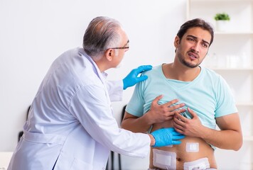 Injured young man visiting experienced male doctor