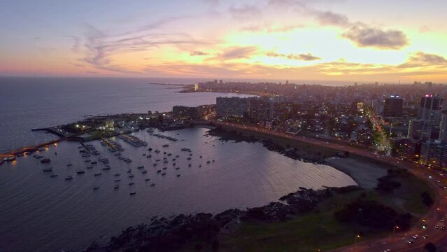 Aerial scene over the Rambla of Montevideo and Buceo port buildings by the sea at sunset, Uruguay