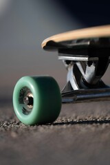Vertical closeup of a skateboard on an asphalt road © Wirestock