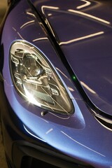 Vertical closeup of the headlight of a modern purple car