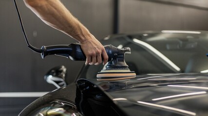 Technician polishing the surface of a modern black car