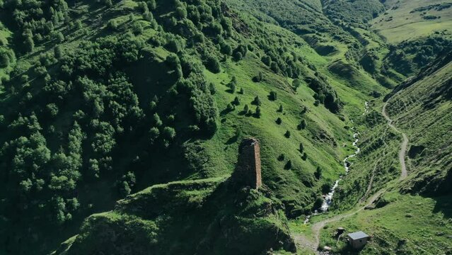 Aerial view of ruins of ancient Svan tower in beautiful amazing gorge landscape of spring greenery. Drone video