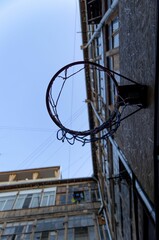 Aged basketball hoop suspended from the side of a red brick wall © Wirestock