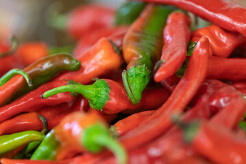Close up of a bushel of ripe red chili peppers with green stems.