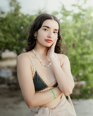 full body portrait of a young girl sitting in the bay of santa marta in colombia, looking at the camera dressed casually.