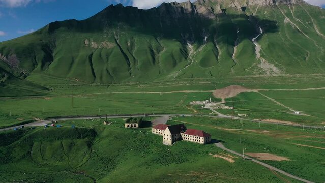 Abandoned village on green slopes of high mountains. Aerial view, drone video