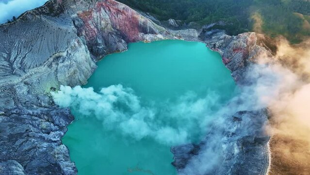 Aerial view Drone shot of fog at Kawah Ijen volcano with turquoise sulfur water lake and sunrise light.Amazing nature landscape view at East Java,Indonesia.Beautiful light Natural landscape background